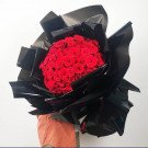 A large bouquet of 150 red roses wrapped in black paper.