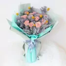 Bouquet of pink roses, yellow craspedia, and grey fillers, wrapped in mint green paper with a grey ribbon.