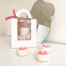 Flower scented candles in a gift box with a mirror reflection.