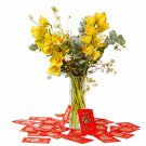 Yellow orchids in a vase with red envelopes scattered around.