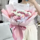 Pink and white bouquet of roses and daisies with pink ribbon.
