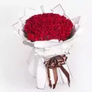 A large bouquet of 200 red roses wrapped in white paper with a brown ribbon.