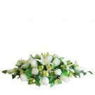 White roses and lilies with green leaves in a low floral arrangement.