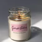 A lit candle in a glass jar with a label that reads "Goodnight Darling, Cherry Blossom & White Jasmine."