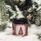 Jar candle with a red label depicting a Christmas tree and text "Warm & Sweet 100g" on snow with pine branches.