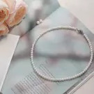 A delicate pearl necklace lies on a book, with pink roses nearby.