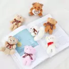 Seven small teddy bears, including pink, white, and brown, are scattered on an open book.