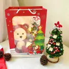 Christmas gift bag with teddy bear, tree, Santa, and pinecones.