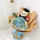 Graduation bouquet with blue hydrangeas, baby's breath, and a teddy bear in a cap and gown.