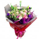 Bouquet of pink, white, and purple roses, daisies, and lisianthus, wrapped in purple and grey paper with red netting and a pink ribbon.