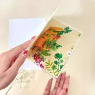 Pop-up birthday card with 3D garden scene and hands opening it.
