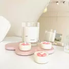 Flower-shaped tealights and a jar candle on a pink tray.