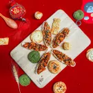 Assortment of Vietnamese Tet cookies, nuts, and treats on a wooden board.