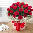 A hat box of red roses and baby's breath with a red ribbon.