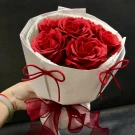 Red soap roses in white paper wrapping with red ribbons.