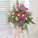 Pink roses, lotus, and green carnations on a wooden stand with a pink bow.