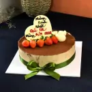 Tiramisu cake with strawberries, white chocolate hearts, and a green ribbon.