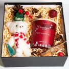 Christmas gift box with a teddy bear, candle, cinnamon, and pinecone.