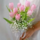 Pink tulips and baby's breath bouquet tied with a white lace ribbon.