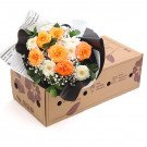 Bouquet of orange roses, white daisies, and baby's breath in a cardboard box.