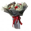 Bouquet of red roses, white carnations, and baby's breath in grey paper with a red ribbon.