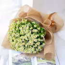 Bouquet of white chamomile flowers wrapped in burlap with a ribbon.