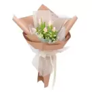 Pink tulip and tanacetum bouquet wrapped in brown and white paper with a ribbon.