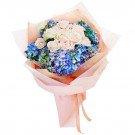 Bouquet of pink roses and blue hydrangeas in pink wrapping paper.