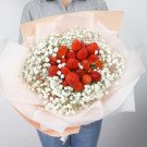 Bouquet of strawberries and baby's breath flowers wrapped in peach and pink paper.
