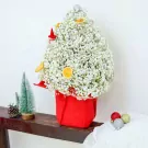 A white baby's breath Christmas tree in a red pot with dried orange slices and a gnome.