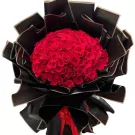 Bouquet of 99 vibrant red roses wrapped in black and gold paper.