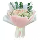 A bouquet of pale pink roses, baby's breath, and eucalyptus leaves, wrapped in pink and white paper with a ribbon bow.