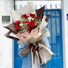 Red and white rose bouquet with baby's breath, wrapped in brown and cream paper, tied with a brown ribbon.