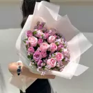 Pink and lavender roses arranged in a bouquet with light pink wrapping paper.