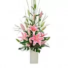 Pink lilies and greenery in a white vase.