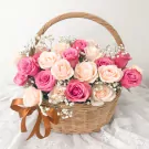 Basket of pink and cream roses with baby's breath, tied with a bronze ribbon.