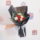Bouquet of red and white roses with silver ribbon on black wrapping paper.