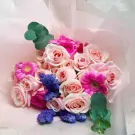 Bouquet of pink roses, pink gerbera daisies, blue statice flowers, and eucalyptus leaves.
