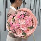 Pink roses and carnations in a soft pink bouquet with ribbon accents.