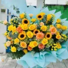 Bouquet of yellow and orange roses and sunflowers with blue paper wrapping.