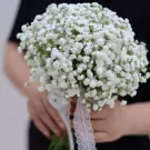 A bridal bouquet of white baby's breath flowers tied with lace ribbon.