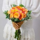 Bridal bouquet of orange and pink roses with greenery.