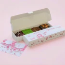 Brownie cake box with "MARCH" written in pink, filled with assorted brownies and topped with almonds and cranberries.