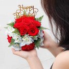 Birthday flower arrangement with red roses, red carnations, hydrangeas, and "Happy Birthday" topper.