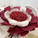 Red blooming bouquet with many red roses, white and red wrapping paper, and a "Happy Day" card.