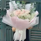 Pink roses and baby's breath bouquet with eucalyptus leaves, wrapped in pink and white paper.