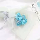 Bouquet of four light blue artificial roses with white mesh and a grey ribbon.