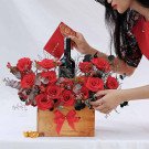 Gift box with red roses, bottle of red wine, and red envelope.