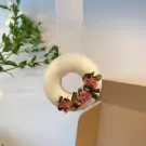 White donut-shaped wax ornament with pink dried flowers, hanging by a ribbon.