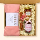 Gift box with pink herbal pillow, honey, rose tea, and cinnamon sticks.
